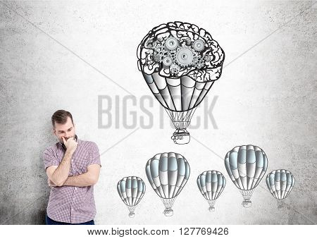 Businessman with airballoons and gears skecth on concrete wall