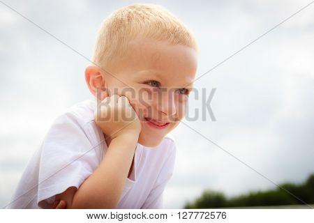 Pensive boy child thinking and daydreaming. Thoughtful kid leaning on his hand looking forward. Imagination.