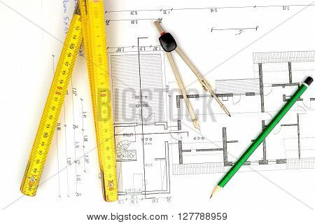 building plan with pencil folding yardstick and compass on wooden table