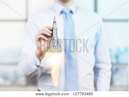 Start up concept with businessman holding rocket ship miniature