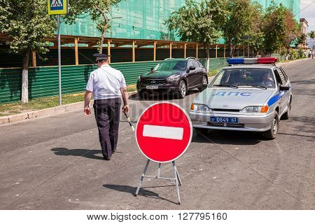 SAMARA RUSSIA - JUNE 16 2015: Russian police officer and patrol vehicle parked at the street in summer day