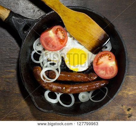 Fried eggs in a frying pan on wooden background