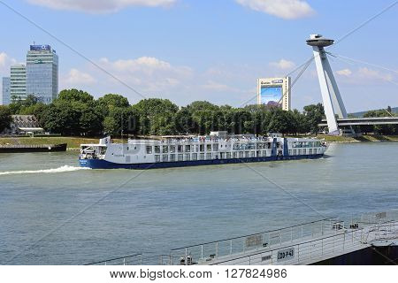 BRATISLAVA SLOVAKIA - JULY 10: Cruise Ship at Danube River Bridge in Bratislava on JULY 10 2015. River Cruise Ship Pass Under Famous UFO Bridge in Bratislava Slovakia.