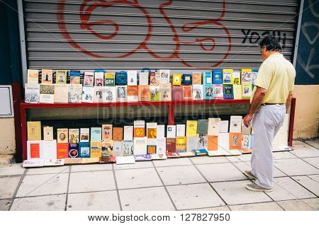THESSALONIKI, GREECE - MAY 27, 2015: A man chooses a book in a bookshop. Books exhibited in the street.