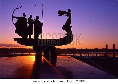 Founders of Kiev monument silhouette against sunrise scene.