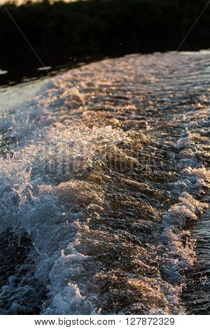 Water splash from motorboat at sunset in the Okavango Delta Botswana Africa.