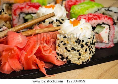 Delicious multicolored sushi rolls served on black board with chopsticks wasabi sesame seeds closeup food photography