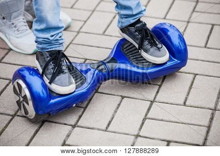 Kid standing on a modern blue electric mini segway or hover board scooterin outdoors. Popular new city transport that is easy and fun to ride and makes no air pollution to the atmosphere
