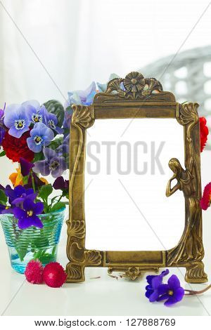 Colorful violets and pancies cut flowers, copy space on empty antique frame