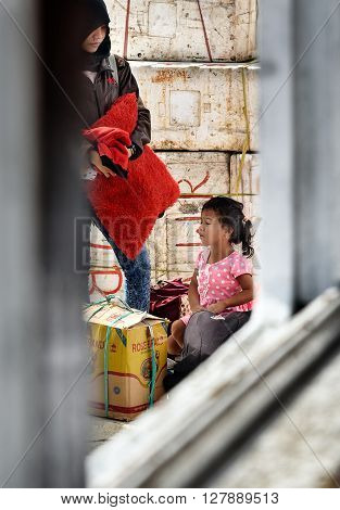 Wakai Indonesia - Dec 16 2015: Unidentified Indonesian mother and daughter on the pier through ship window from Ampana. Togean Islands or Togian Islands in the Gulf of Tomini. Central Sulawesi.
