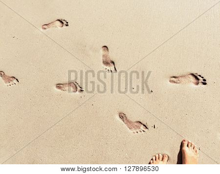 Feet and steps marks on sunny sand beach by sea, summer travel photo,  close up footprints in sand, yellow sand with step marks, vacation by sea, summer holiday, girl on holiday, Bali, Indonesia