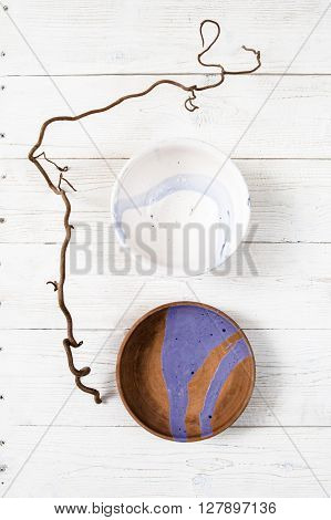 Top view empty creative handmade pottery plates with turquoise pattern on rustic wooden table.  Flat lay set of colorful clay dishes on white wooden background.