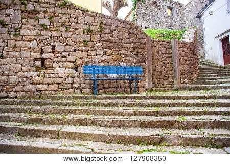 Blue bench next to the stones wall in labin
