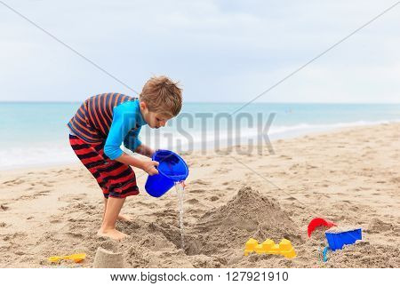 little boy play with sand on summer beach, family vacation