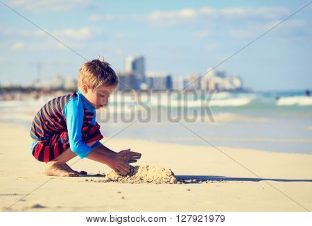 little boy play with sand on summer beach, family vacation