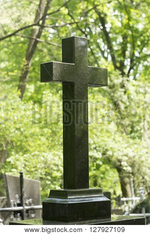 vintage black marble cross at a cemetery