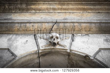 A stone skull placed near the entrance of a charnel house in an Italian graveyard.