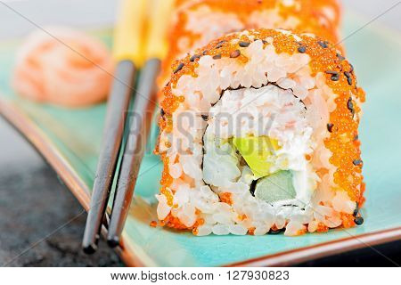 California maki sushi with masago an chopsticks. Roll made of crab meat, avocado, cucumber and masago.