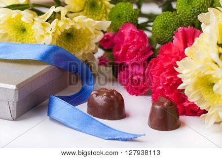 Chocolate Candy And Flowers Over White
