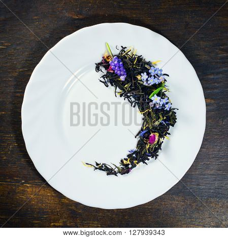 Dried tea in white plate on wooden background