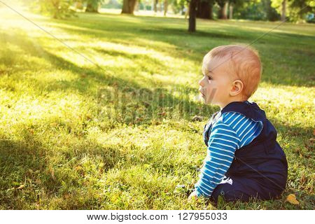 little nine month old baby sitting in the park in beautiful evening