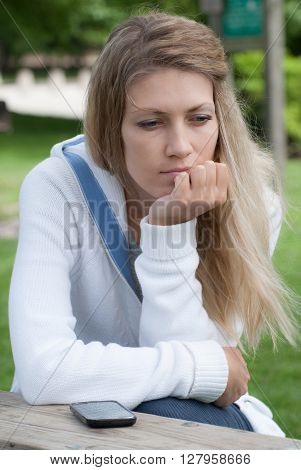 Young pensive girl on a park bench