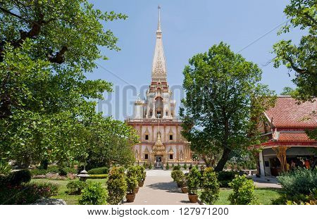 PHUKET, THAILAND - FEB 6, 2016: Tall structure of historical Wat Chalong temple inside green park with trees on February 6, 2016. First written mention about the buddhist monastery belongs to 1837