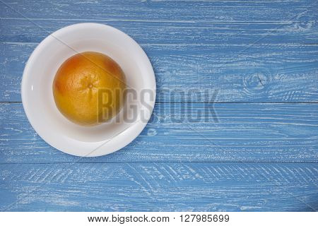 grapefruit on white plate on blue wood background