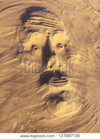 Sand sculpture mask on sandy beach in Goa, India