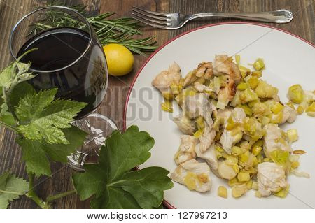 chicken with leeks , sauteed leeks fried chicken with a glass of wine , vine leaves