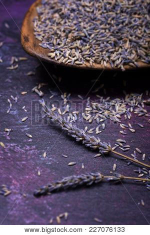 Sprigs of lavendar and scattered flowers with a bowl of dried lavender in the background. Selective focus. 