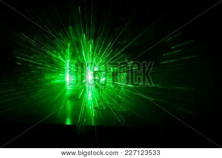 Two Glasses Of Vodka With Bottle On Dark Foggy Club Style Background With Glowing Lights (laser, Sto