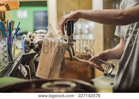 Pouring Fresh Beer. Close-up Of Young Bartender Pouring Beer While Standing At The Bar Counter