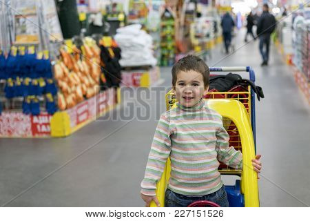 The Boy 4 Years Leaned Out Of The Children's Cart In The Building Store. Dangerous Behavior Of Child
