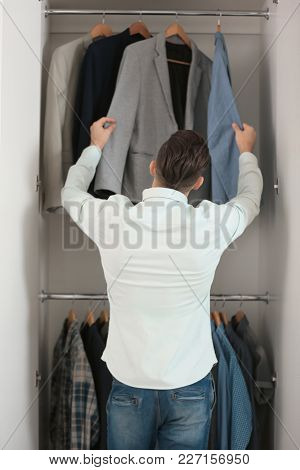 Man picking jacket from closet. Fashionable wardrobe