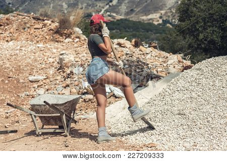 Beautiful Naked Woman In The Red Peaked Cap With A Wheelbarrow For Cement And The Shovel Digging Sto