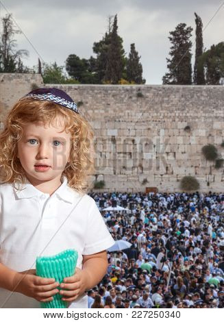 Beauteous little boy with blue eyes and blond side curls, in skullcap. Autumn Jewish holiday Sukkot.  The greatest shrine of Judaism is the Western Wall of the Temple