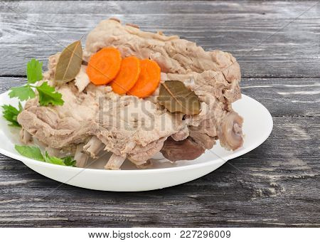 Fragment Of The White Dish With Piece Of The Boiled Pork Ribs With Parsley, Carrot Slices And Bay Le