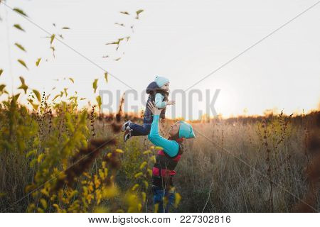 Woman In Turquoise Hat Standing At Dry High Grass Background High Toss Up Little Cute Child Baby Boy