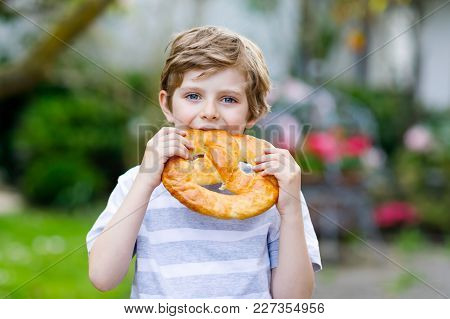 Adorable Little Kid Boy Eating Huge Big Bavarian German Pretzel. Happy Blond Child Enjoying Tasteful