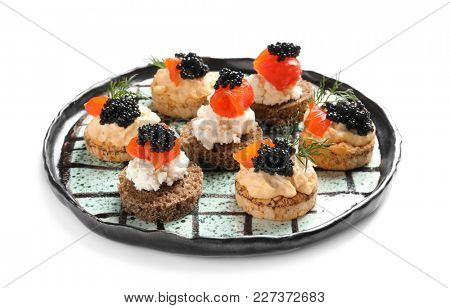 Plate of delicious canapes with black caviar on white background