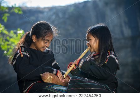 Daklak, Vietnam - Mar 9, 2017: Two Ede Ethnic Minority Little Girls Learning To Play The Flute In Fo