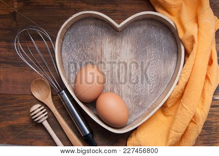 Rustic Kitchen Tools For Bakerry Or Cooking. Raw Eggs With Wooden Spooon, Orange Napkin, Heart Shape