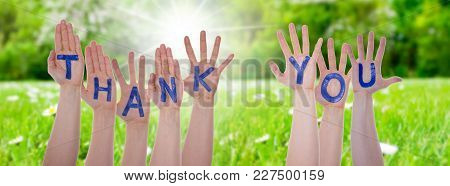 English Word Thank You On Hands Of White Caucasian People. Sunny Grass Meadow In Background.