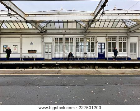 TROON, SCOTLAND - FEBRUARY 19, 2018: Passengers waiting for the train at Troon Station in Troon, South Ayrshire, Scotland, UK.