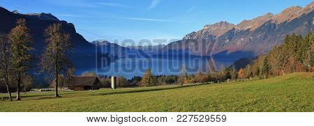 Autumn Scene In Brienz. Green Meadow, Houses And Lake Brienzersee. Mount Augstmatthorn. Landscape In
