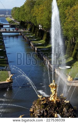 PETERHOF, ST. PETERSBURG, RUSSIA - JUNE 4, 2017: Tourists walking around the Sea canal and the Grand Cascade. The cascade was built in 1715-1724 and is one of the remarkable fountain constructions