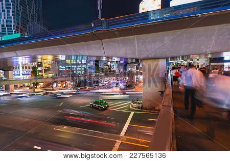 Motion Blurred View Of People And Traffic Crossing A Busy Intersection In Shibuya, Tokyo, Japan