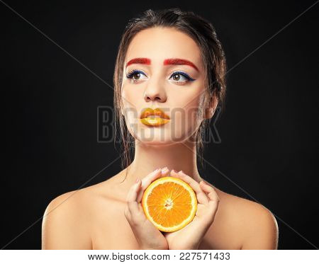 Young woman with dyed eyebrows and half of orange on black background