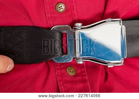 Male Airline Passenger Unbuckling His Seatbelt Buckle Lifting The Lever With His Thumb As He Pulls T